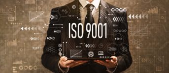 ISO 9001 with businessman holding a tablet computer on a dark vintage background